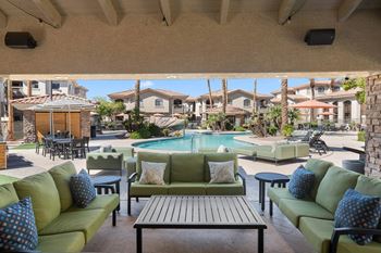 A patio with a pool and green couches.